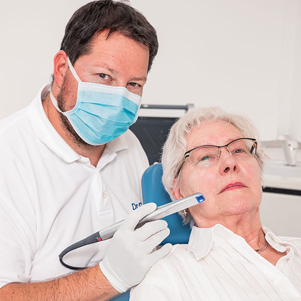 Dachau-Zahnarzt-Dr--Gitt---Zahnersatz Der Dachauer Zahnarzt Dr. Gitt behandelt eine Seniorin mit dem Intraoralscanner.
