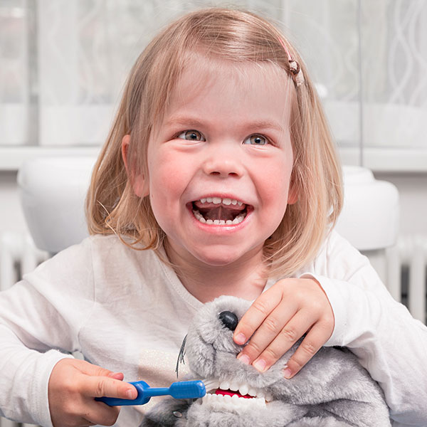 Familienzahnarzt-Dr.-Gitt---kleine-Patienten-quad Familienzahnarzt Dr. Gitt erklärt kleiner Patientin das Zähneputzen mithilfe eines Stoff-Krokodils.