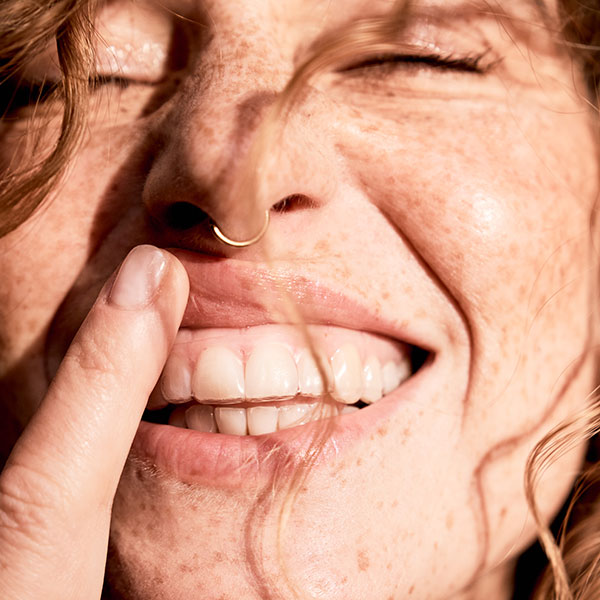 Zahnschiene-Dachau Lächelnde Frau mit einer Aligner Zahnschiene, die kaum sichtbar ist.