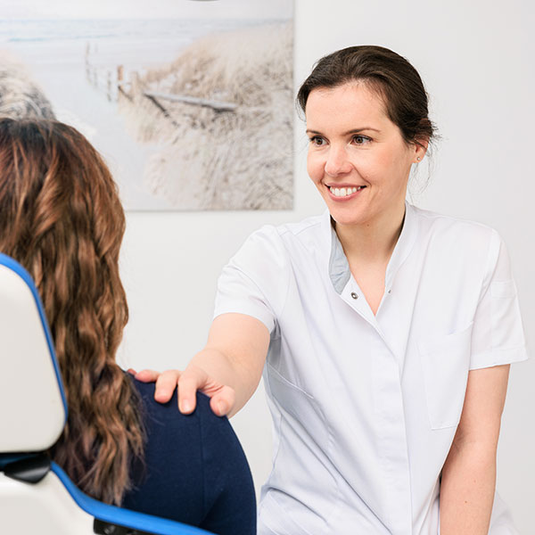 Behandlung von Angstpatienten Zahnärztin behandelt eine Angstpatientin und beruhigt sie freundlich.